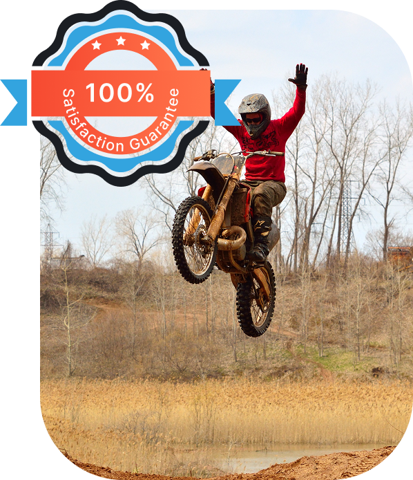 Motocross rider performing a stunt mid-air with one hand raised, featuring a "100% Satisfaction Guarantee" badge.