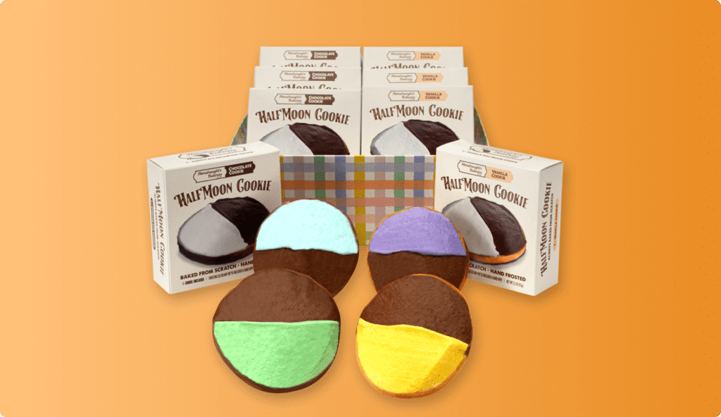 Boxes of Half Moon Cookies with colorful frosted varieties displayed in front on an orange background.