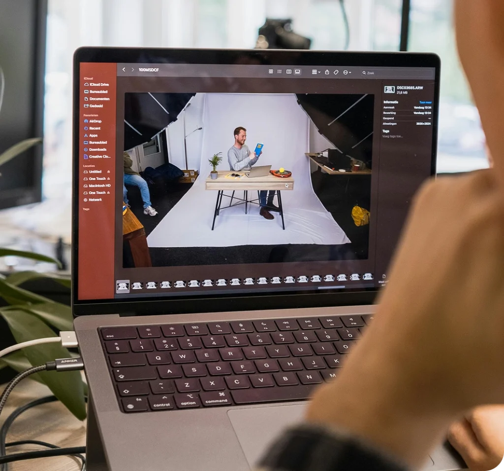 Person reviewing a product photoshoot on a laptop screen in a studio setting.