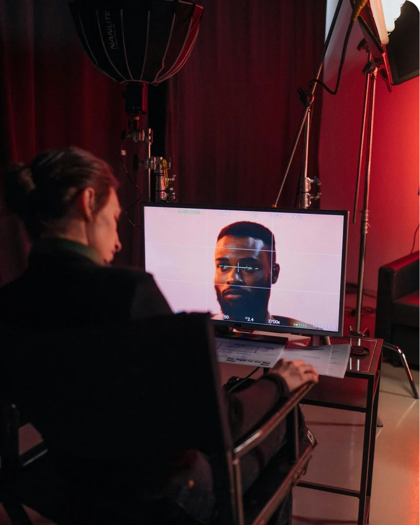 Film director reviewing footage of an actor on a monitor during a studio shoot.