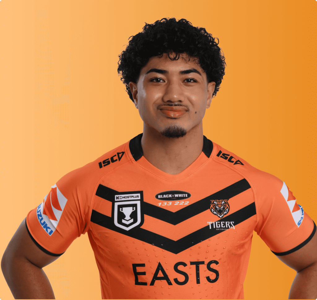 Male athlete wearing an orange Easts Tigers rugby jersey posing confidently against an orange background.