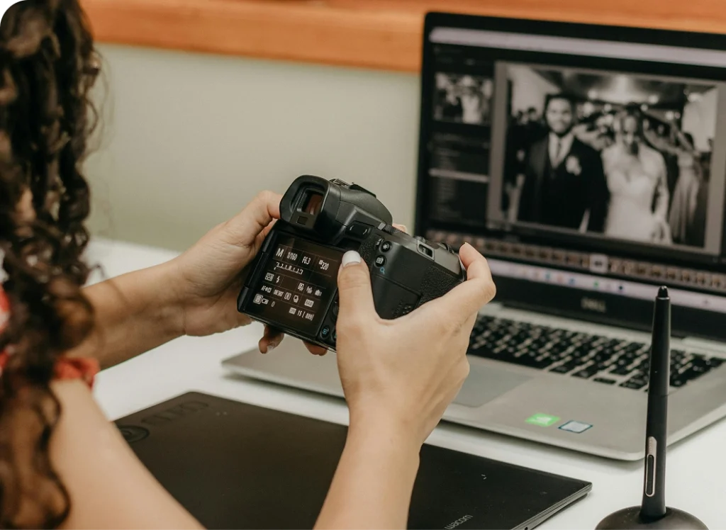 Photographer reviewing camera settings while editing wedding photos on a laptop.